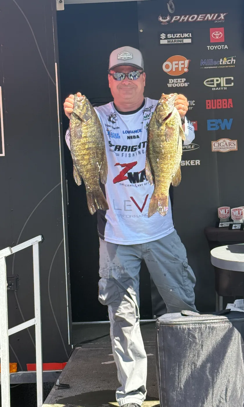 Brian Barde at a Major League Fishing weigh-in holding two smallmouth bass